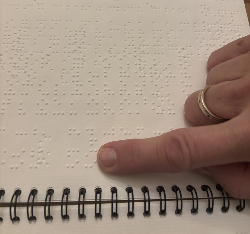 Un texte en Braille avec un doigt dessus